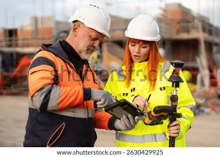 Construction workers collaborate while reviewing data on tablet at building site