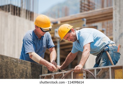 Construction workers collaborating in the installation cement formwork frames