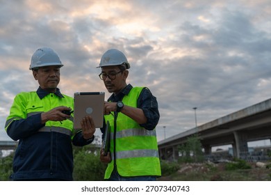 Construction workers collaborating on project urban environment digital technology evening sky professional insight