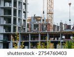 Construction workers efficiently building a large concrete residential building, using heavy equipment like a tower crane to construct modern urban housing infrastructure or a commercial property