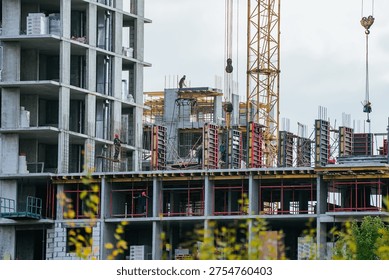Construction workers efficiently building a large concrete residential building, using heavy equipment like a tower crane to construct modern urban housing infrastructure or a commercial property