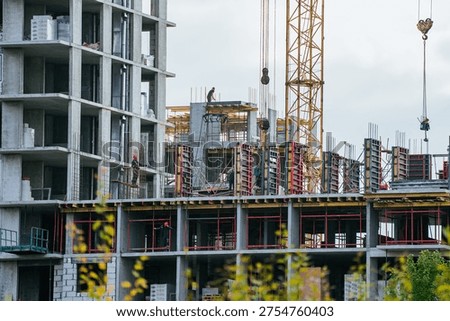 Construction workers efficiently building a large concrete residential building, using heavy equipment like a tower crane to construct modern urban housing infrastructure or a commercial property
