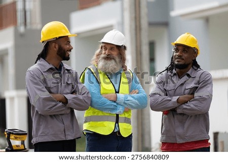 Construction workers and engineer wearing safety helmets and reflective vest discussing project at building site. Teamwork in construction industry, engineering collaboration and workforce concept.