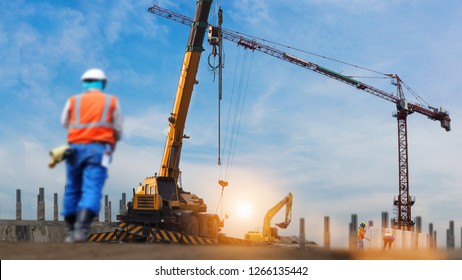 Construction Workers Engineer Working In Construction Site Under View Of Crane Excavator In Sun Set Background
