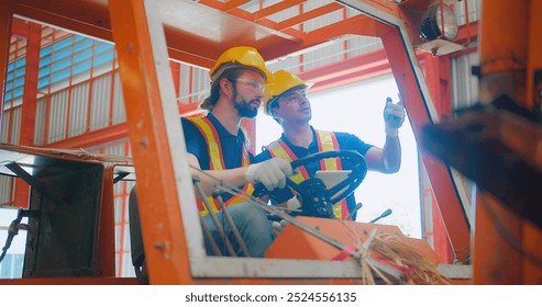 Construction workers engineers in yellow hard hats and safety vests are discussing operate a construction lift machinery within an industrial environment, focus on occupational safety and teamwork - Powered by Shutterstock