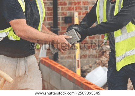 Construction Workers Exchanging Concrete Blocks at a Residential Build Site During the Day