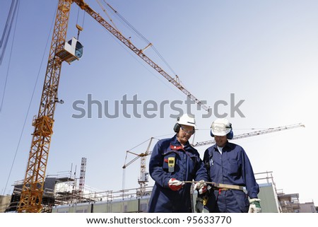 construction workers with giant cranes, scaffolding and machinery,  background slightly blurred