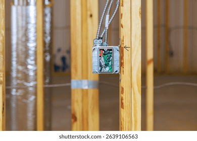 Construction workers install an electrical box in newly framed room while building house.