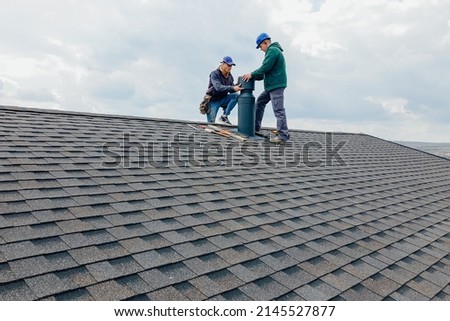 Construction workers Installing chimney and building construction concept. Contractor Builder with blue hardhat on the roof caulking chimney