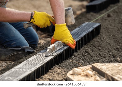 Construction workers installing drainage system channel components at building site