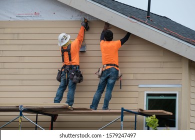 Construction Workers Installing Vinyl Siding Facade On Scaffolding System. USA. Los Angeles -December 1, 2019.