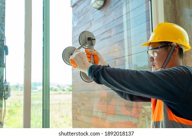 Construction Workers Installing A Window In A New Building,Hand Holding A Special Tool For Carrying A Glass Pane. 