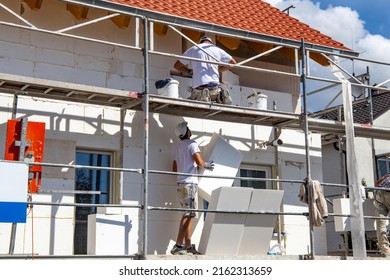 Construction workers insulates house facade