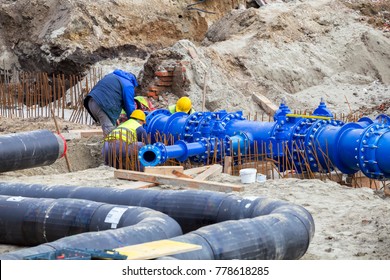 Construction workers laid water system pipeline at construction site. City construction of water supply pipeline with gate valves. Construction of drinking water pipes with gate valves in a trench.