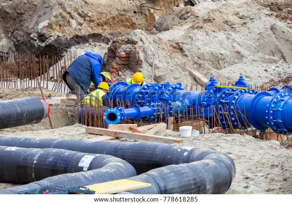 Construction workers laid water system pipeline at construction site. City construction of water supply pipeline with gate valves. Construction of drinking water pipes with gate valves in a trench.