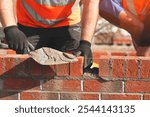 Construction workers laying bricks at a building site during daylight, showcasing skillful masonry and teamwork efforts