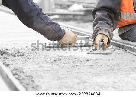 Construction workers leveling concrete pavement.