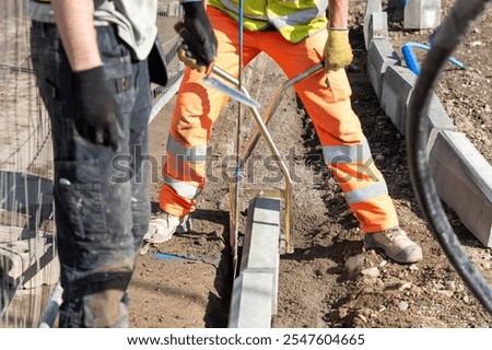 Construction workers placing concrete kerb on concrete for sidewalk