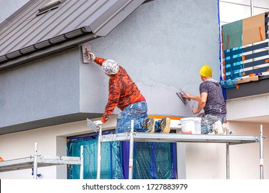 Construction workers plaster the facade of the house. Application Of Facade Plaster.