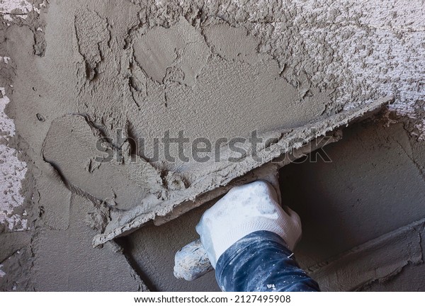 Construction\
workers plaster the facade of the house. Worker plastering tool\
plaster marble on interior plaster\
rough
