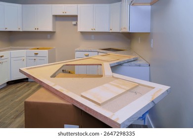 Construction workers prepare to install marble countertop in contemporary kitchen with white cabinets.