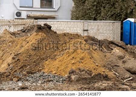 Construction workers are preparing a site with large mounds of dirt and gravel to begin new residential building projects in the neighborhood.