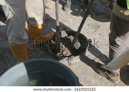 Construction workers preparing soil in a metal ring mold for an on-site permeability test