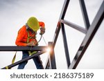 Construction workers put on safety gear to work on the way to install the factory roof welding structure.