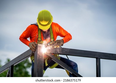 Construction Workers Put On Safety Gear To Work On The Way To Install The Factory Roof Welding Structure.