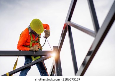 Construction Workers Put On Safety Gear To Work On The Way To Install The Factory Roof Welding Structure.