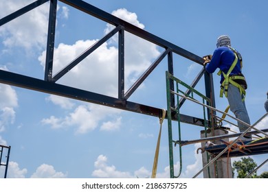 Construction Workers Put On Safety Gear To Work On The Way To Install The Factory Roof Welding Structure.