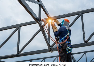 Construction Workers Put On Safety Gear To Work On The Way To Install The Factory Roof Welding Structure.