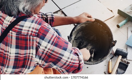 Construction workers or technicians is mixing the cement in the bucket using a trowel to sit on the construction site with safety standards. Concept Social Security of Labor