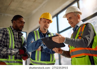 Construction workers and their project manager working on digital tablet at building site. 