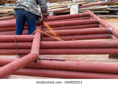 Construction Workers Are Using Grinding Machines On Large Steel Pipes. Used As A Roof Pole. Sparking While Working Red Painted Steel Pipe To Prevent Rust And Look Beautiful