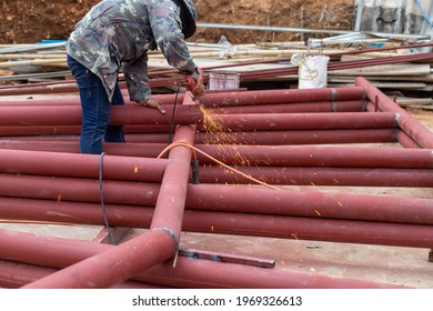 Construction Workers Are Using Grinding Machines On Large Steel Pipes. Used As A Roof Pole. Sparking While Working Red Painted Steel Pipe To Prevent Rust And Look Beautiful