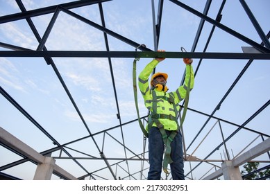 Construction workers wear safety harnesses and safety lines working at high places construction workers work at heights by wearing seat belts when doing construction work for safety. - Shutterstock ID 2173032951