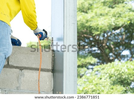 Construction workers welding rebar to steel pole columns to stabilize the masonry to increase the stability of the brick wall.