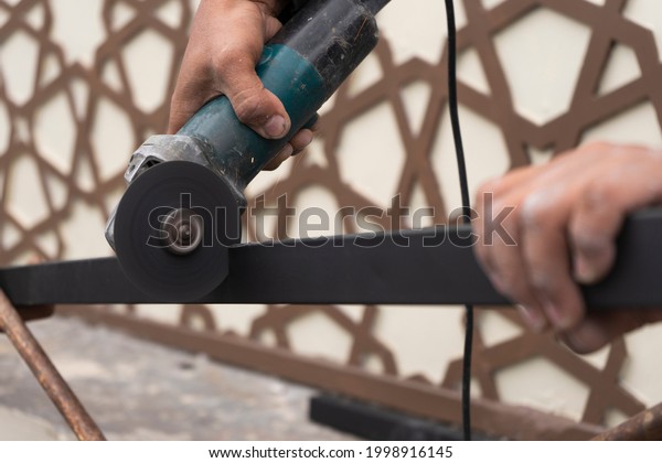 construction workers will cut black hollow iron\
with a grinder