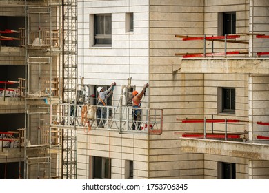 Construction workers work on a facade building in a suspended cradle. Israel Ashkelon May 2020