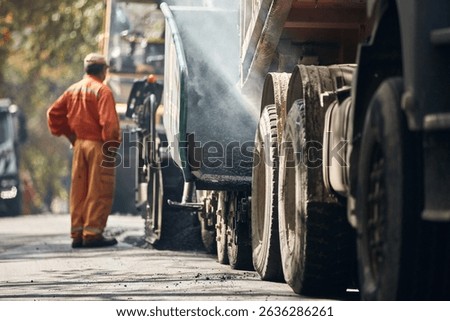 Construction workers working on a new asphalt layer on a public street.