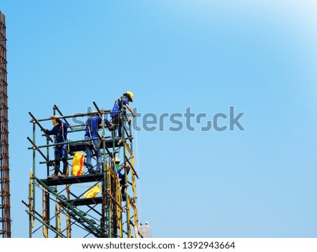 Construction workers working on scaffolding with blue sky at construction site