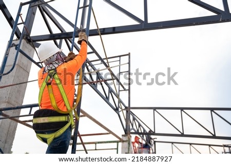 Construction workers are working on steel roof trusses with Fall arrestor device for worker with hooks for safety body harness on the construction site.