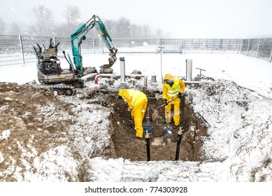 Construction Workers Working Outside In The Cold Snow Repairing A Leaking Water Pipe.