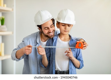 Construction working and repairs. Cheerful dad and his son using measuring tape and wearing safety helmets, dad teaching boy using roulette. Family spending time together at home - Powered by Shutterstock