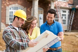 Construction: Young Couple Look At Home Plans With Builder.