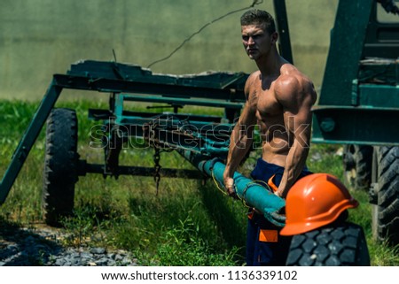 Constructor concept. Constructor pull truck trailer. Constructor worker with six pack and ab muscular torso. Strong constructor on construction site.