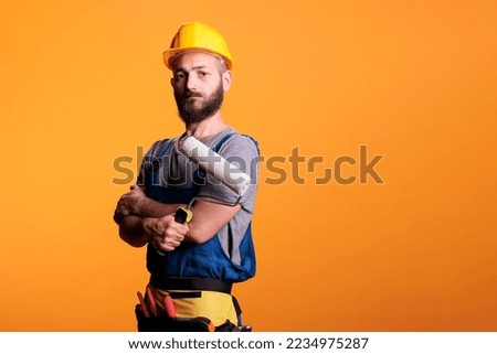 Constructor expert using rolling brush to do painting job, working on renovating project to color walls. Repairman contractor holding roller paintbrush for redecoration and renovation.