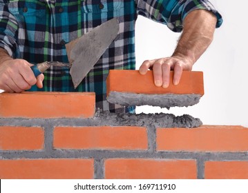 Constructor hand holding a brick and building a wall.