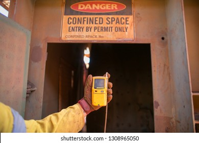 Constructor worker hand holding gas test leak detector device while commencing safety gas testing atmosphere at main entry and exit on confined space door prior to work construction site, Australia   